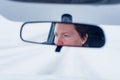 Face of a female driver in car rear-view mirror while driving in bad conditions during snow blizzard Royalty Free Stock Photo