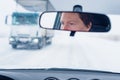 Face of a female driver in car rear-view mirror while driving in bad conditions during snow blizzard Royalty Free Stock Photo