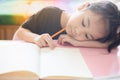 Face focusing of adorable asian child girl is writing on her paper book in the room at home with sunlight shows tired and boring Royalty Free Stock Photo