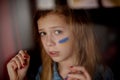 Face of a frightened girl, a painted heart on the cheek in yellow-blue colors of the Ukrainian flag. Russia Royalty Free Stock Photo