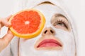 Face fruit peeling mask, spa beauty treatment, skincare. Young woman getting facial care at spa salon, mud clay mask on Royalty Free Stock Photo