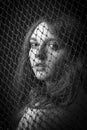 Face of girl behing a net on a dark background with a back light Royalty Free Stock Photo