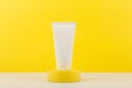 Face or hands cream in white tube on yellow podium against yellow background with copy space Royalty Free Stock Photo