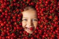 The face of a happy, cheerful child surrounded by a large number of cherries Royalty Free Stock Photo