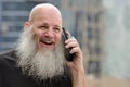 Face of happy mature bald bearded man talking on the phone in the city Royalty Free Stock Photo