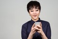 Face of happy young androgynous Asian transgender woman using phone