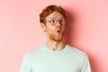 Face of intrigued young man with ginger hair and beard, raising eyebrows surpirsed and looking at upper right corner