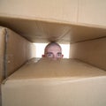 Face looking trough window in pile cardboards Royalty Free Stock Photo