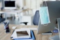 Face mask hanging on computer screen in an empty office