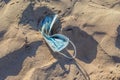 Abandoned used face mask on the beach with outdoor sun lighting Royalty Free Stock Photo