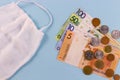 Face mask and money background. Belarusian banknotes and coins on a blue background, the connection of medicine and money