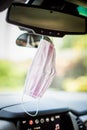 Face mask PPE in car hanging from rear view mirror Royalty Free Stock Photo