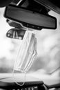 Black and white Face mask PPE in car hanging from rear view mirror Royalty Free Stock Photo