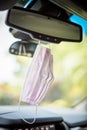 Pink Face mask PPE in car hanging from rear view mirror Royalty Free Stock Photo