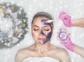 Face mask the skin to beautiful woman. Next to her are Christmas decorations.New Year`s and Cosmetology concept