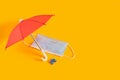 face mask under a red umbrella on yellow background, beach vacation and tourism during the coronavirus epidemic concept Royalty Free Stock Photo