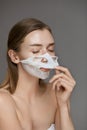 Face mask. Woman taking off white sheet mask from facial skin Royalty Free Stock Photo