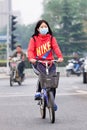 Face-masked female cyclist in smog blanketed city, Beijing, China