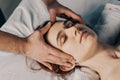 Face massage. Male hands make head massage to a beautiful young woman. Close-up of a woman getting spa treatment Royalty Free Stock Photo