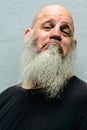 Face of mature bald bearded man making face against concrete wall Royalty Free Stock Photo