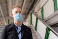 Face of mature businessman with mask going down the stairs of the sky train station Royalty Free Stock Photo