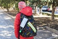 Face medical mask is hanging on school backpack. Schoolboy is going to school throu park.