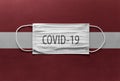 Face Medical Surgical White Mask with COVID-19 inscription lying on Latvia National Flag. Coronavirus in Latvia