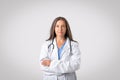The face of modern healthcare. Portrait of confident senior doctor woman posing with folded arms, light background Royalty Free Stock Photo