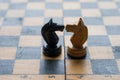 Chess pieces knights facing each other for a standoff on chessboard with blue background. Chess knights confronting each Royalty Free Stock Photo