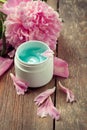 Face organic cream with peonies on an old wooden table
