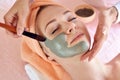 Face peeling mask, spa beauty treatment, skincare. Woman getting facial care by beautician at spa salon, side view, close-up Royalty Free Stock Photo