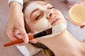 Face peeling mask, spa beauty treatment, skincare. Woman getting facial care by beautician at spa salon, side view Royalty Free Stock Photo