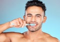 Face portrait, dental and man brushing teeth in studio isolated on a blue background. Wellness, oral health and routine Royalty Free Stock Photo