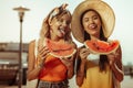 Face-portrait of girlfriends keeping watermelon pieces in hands