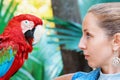 Face portrait of young girl looking at red macaw parrot