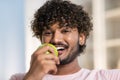 A face of positive smiling mestizo guy in joyful and happy mood. A young charming african or american man eats apple