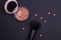 Face powder makeup balls and black brush on black background.