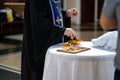 without a face. priest with oil for the anointing at baptism.