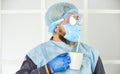 Face protection goggles mask gloves head cover. Personal protective equipment. Guy in mask drink tea coffee using straw