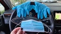 A face protection mask in female hand against a car steering wheel