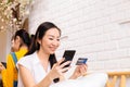 Face of 40s middle aged Asian woman holding credit card and mobile phone in cozy white room Royalty Free Stock Photo