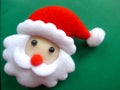 Face of a Santa Claus with beard and red cap, felt, green background