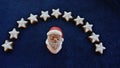 Face of Santa Claus under a garland of home-baked cinnamon stars. Close-up, against a blue background