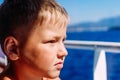 The face of a seven-year-old boy close. Child near the window on the ship