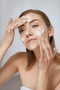 Face skin care. Woman applying facial cleanser on face closeup