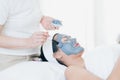 Face Skin Care. Woman doing facial procedures to beautician. The spa staff is applying mud to the face Royalty Free Stock Photo