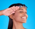 Face, smile and salute with a swimmer woman in studio on. a blue background wearing goggles on her head. Happy, hand