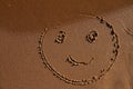 emoticon face painted on jetted beach sand by sea Royalty Free Stock Photo