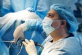 Face of surgeon in mask holding laparoscopic tool