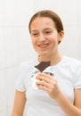 Face of a teenage girl with pimples, acne on the skin, she looks at herself in the mirror and eating a chocolate, concept of